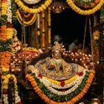 Beautifully decorated idol of baby Lord Krishna illuminated by diyas during the midnight Janmashtami puja.