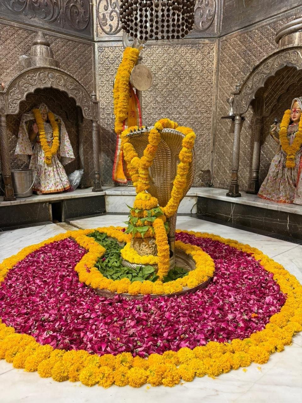 Shiva Linga inside Bhadkeshwar Mahadev Temple in Dwarka decorated with flowers and lamps.